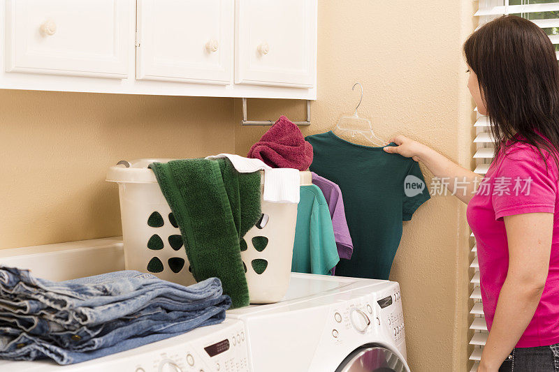 家庭生活:年轻人把刚从烘干机里拿出来的衬衫挂起来