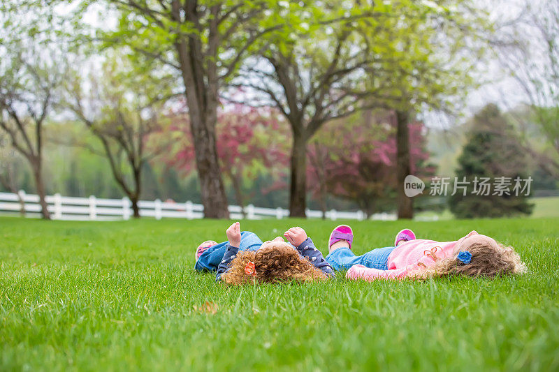 两个年轻女孩躺在草地上看着天空