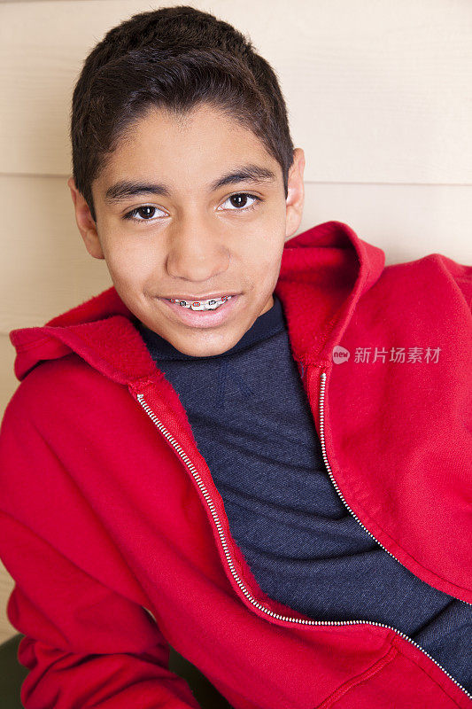 快乐的十来岁的小男孩戴着护具穿着红色的连帽衫