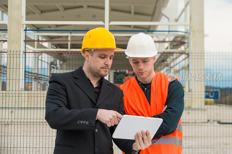 建筑师和建筑工人在平板电脑上看蓝图