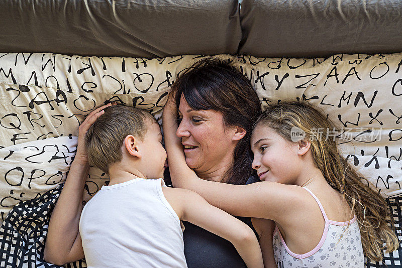 快乐的妈妈和她的孩子们躺在床上