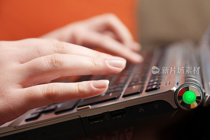 女性手在笔记本电脑键盘上打字的特写