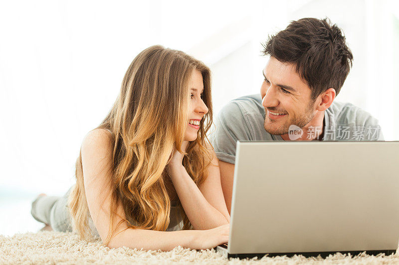快乐的年轻夫妇使用笔记本电脑