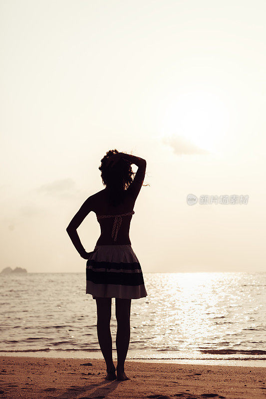 年轻女子站在海滩上望着大海