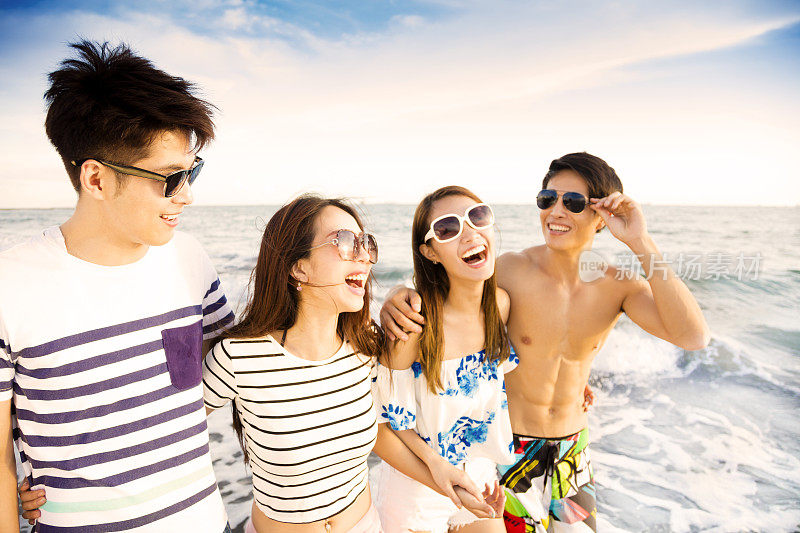 一群快乐的年轻人在海滩上散步享受暑假