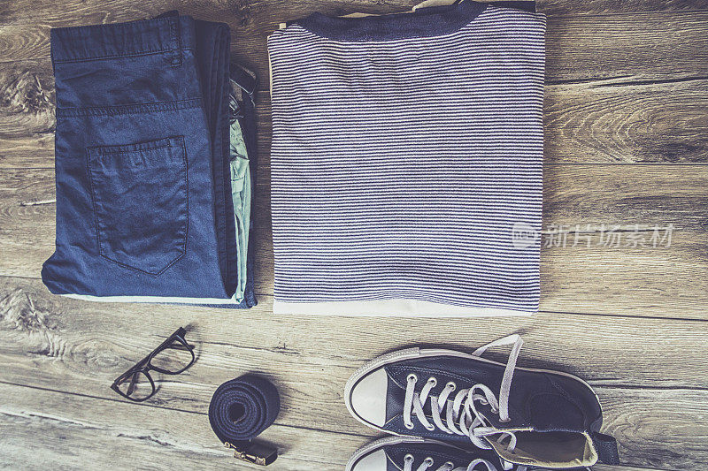 衣服，个人员工和物品概念-关闭折叠的衬衫，裤子和鞋子在家里的桌子上
