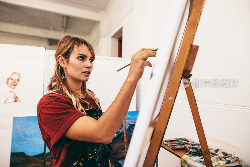 女画家在她的画室的帆布上作画