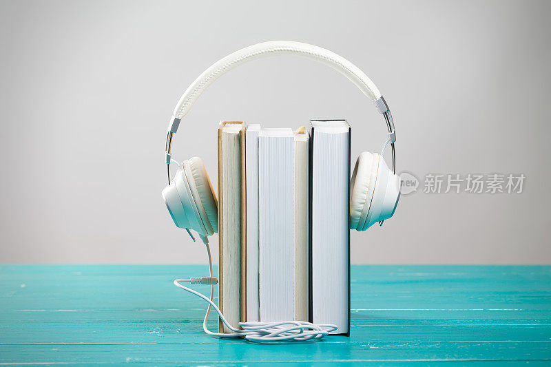 书和耳机在绿松石桌子在有声书的概念