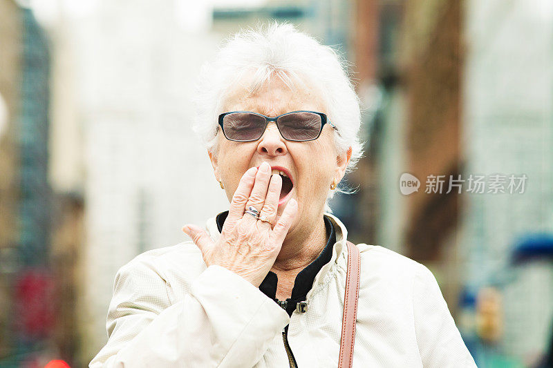 精疲力竭的老女人打哈欠在曼哈顿纽约城市