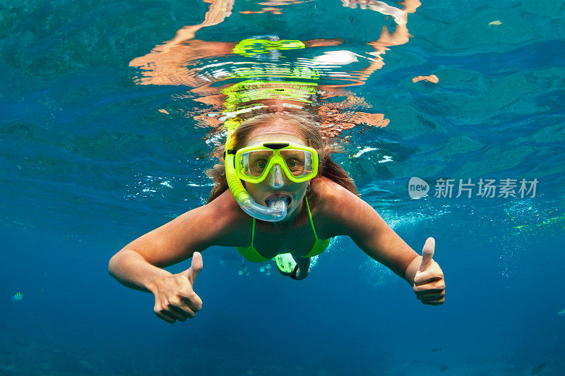 戴着浮潜面罩的女孩和珊瑚礁里的鱼一起潜水