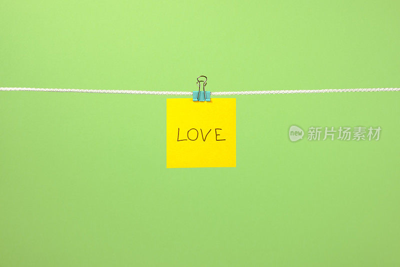 晒衣绳上的黄色纸条，彩色背景上写着“爱”