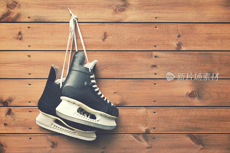 冰球冰鞋挂在钉子上的木板背景上