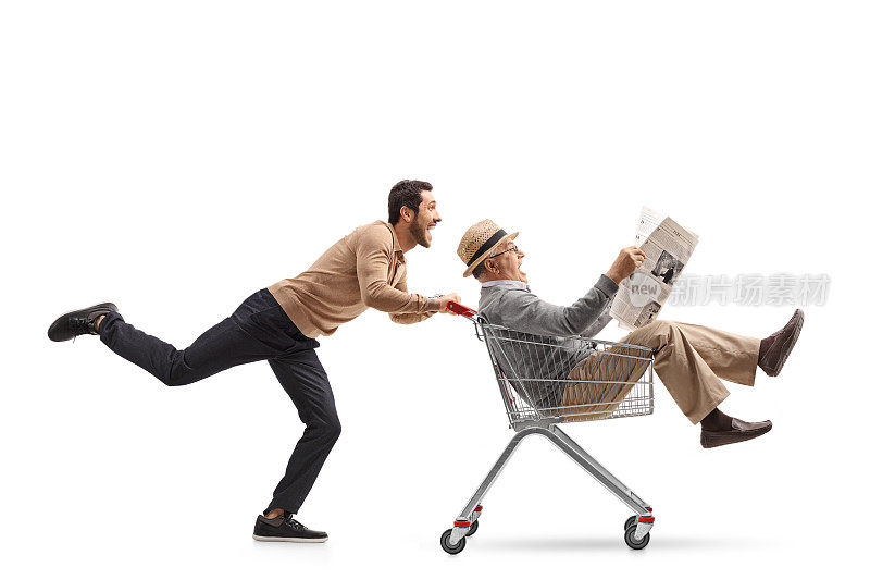 一个成熟的男人拿着报纸坐在购物车里被一个年轻人推着