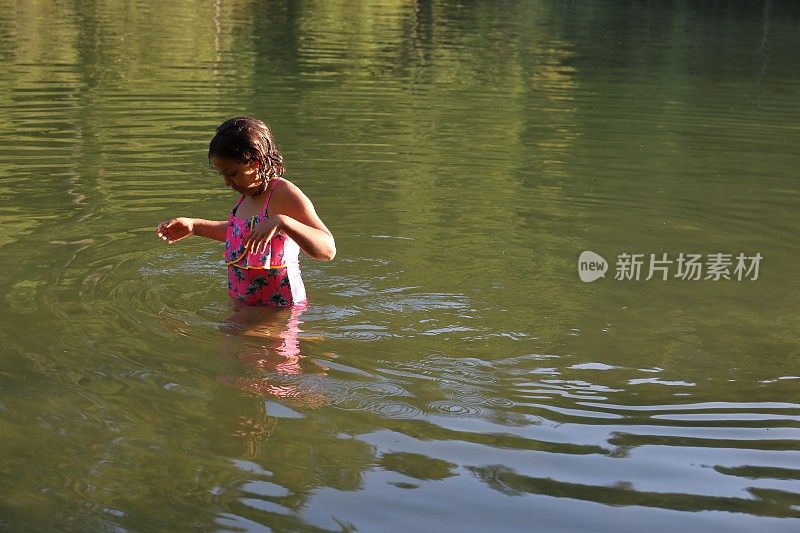 女孩走进淡水湖，在一根圆木上保持平衡