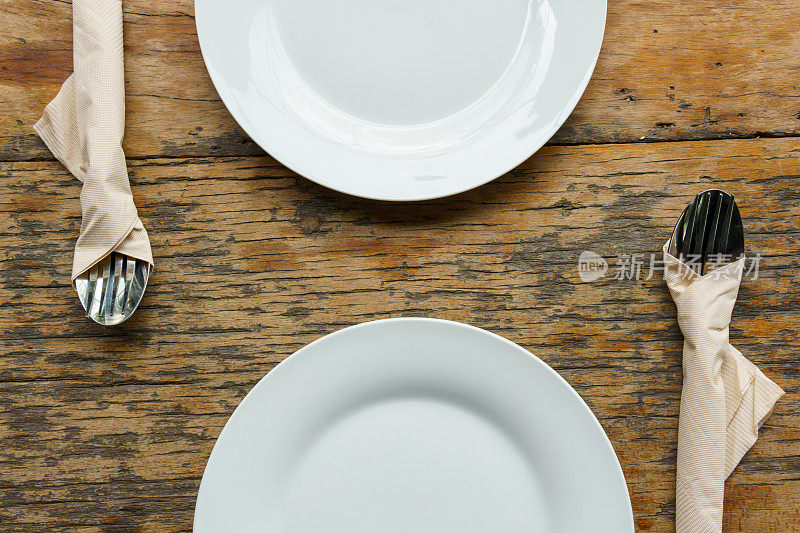 前视图。旧木桌上放着两个带刀叉的白色空盘子。食品的概念。