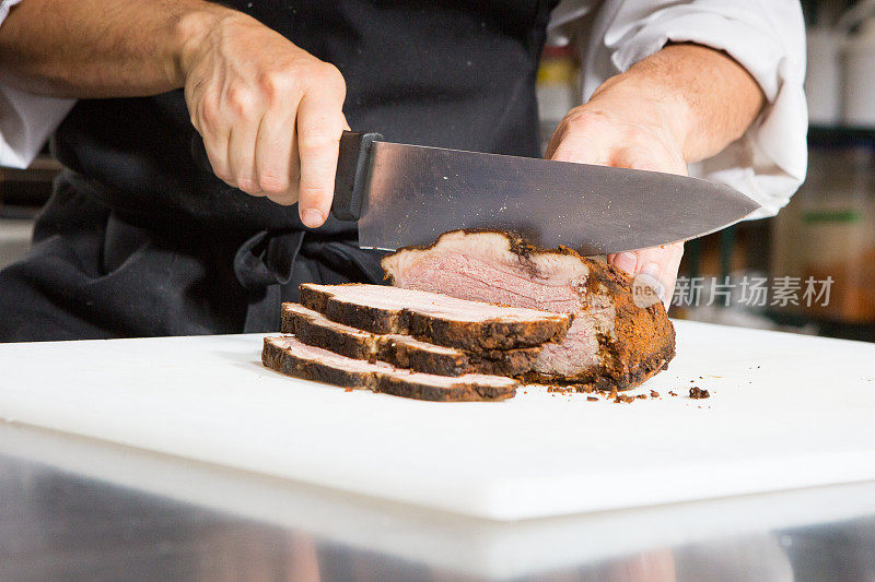 厨师用切肉刀将烤牛肉切成薄片