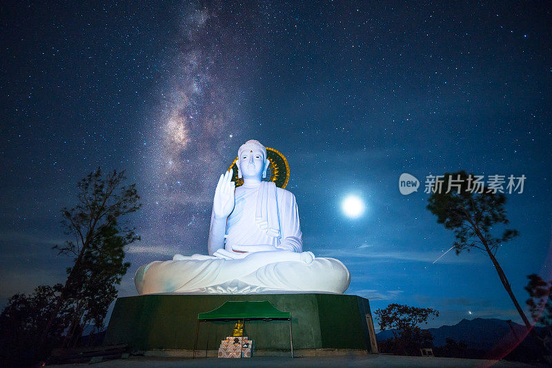 在泰国清莱的一座寺庙里，美丽的夜空和银河覆盖着大佛像。长时间暴露有噪声和纹理。