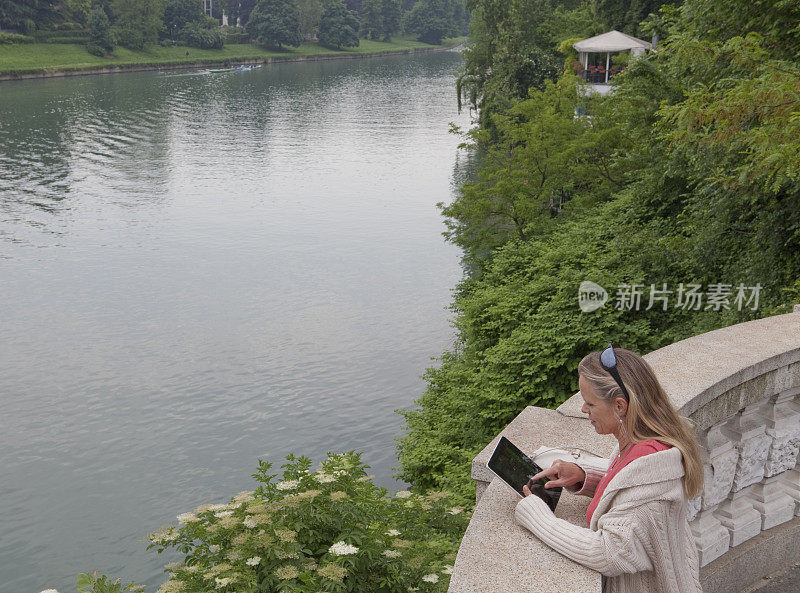 一名女子在河上的阳台上用ipad