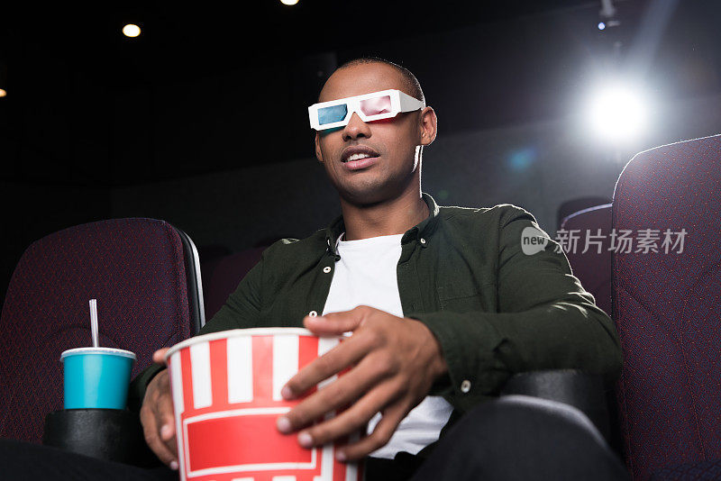 戴3d眼镜的非裔美国人在电影院吃爆米花看电影