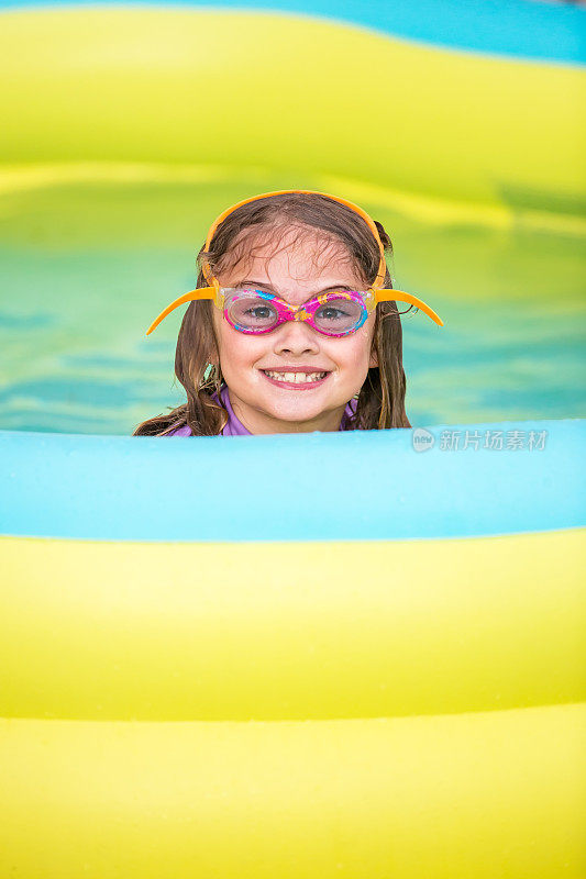 充气游泳池里的小女孩对着相机微笑