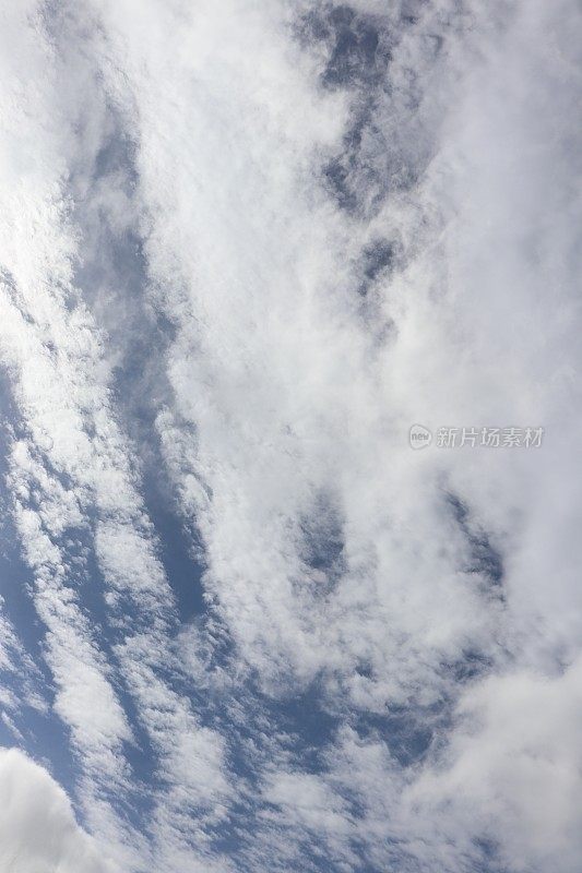 蓝色天空映衬着蓬松、缕缕白云的特写