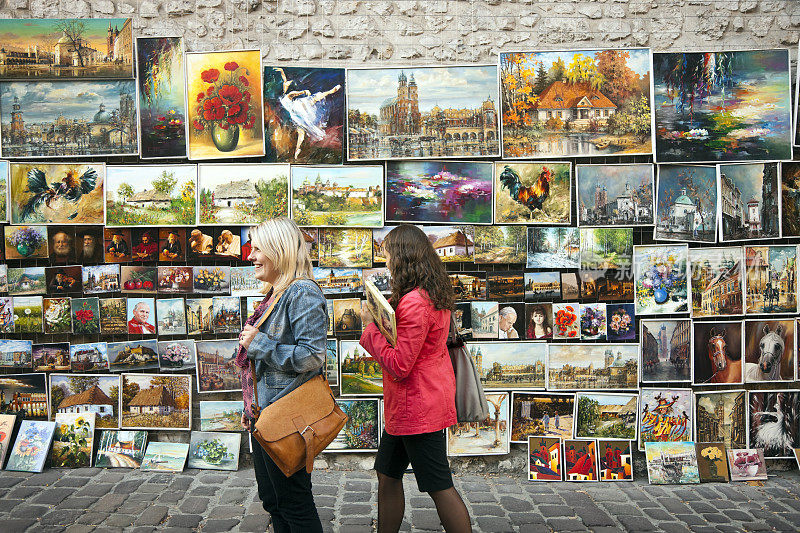 波兰克拉科夫，两名女学生靠着绘画展览墙