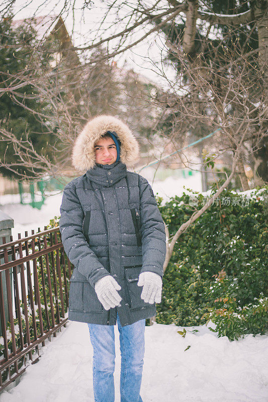 可爱的男孩穿着暖和的衣服在美丽的雪天冬天的森林里玩耍