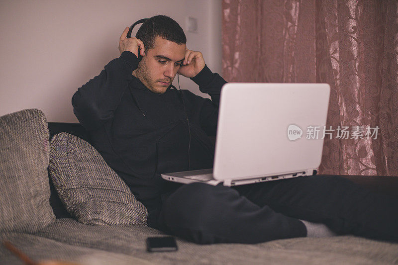 年轻人坐在沙发上使用笔记本电脑