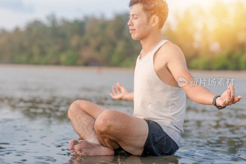 年轻的亚洲男子在日落海滩做瑜伽运动