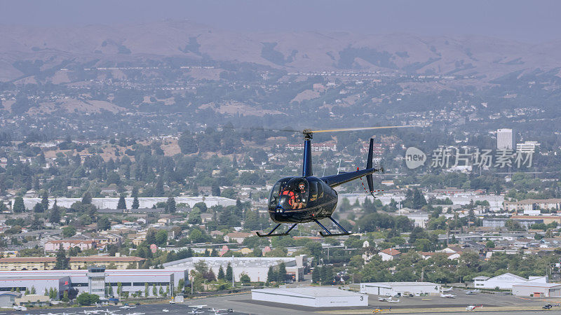 直升机在城市飞行的鸟瞰图，背景是一个小机场