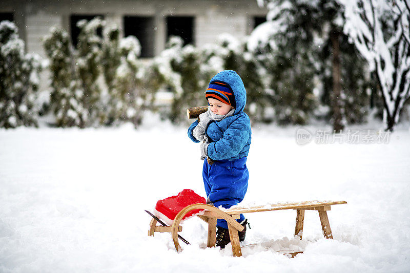 可爱的小男孩在大自然的雪地上修理雪橇