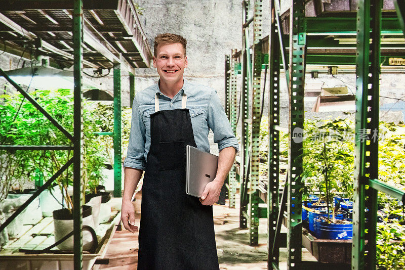 大麻店-一名男性员工正拿着一台笔记本电脑