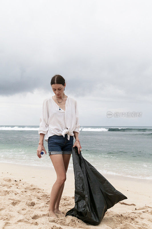 在海滩上捡垃圾的志愿者。Trash-free海域概念。一次性塑料是人类的嗜好，正在破坏我们的星球