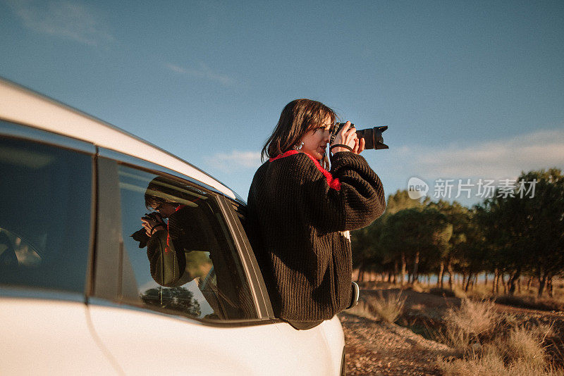 一名年轻女子正用单反相机透过车窗拍照