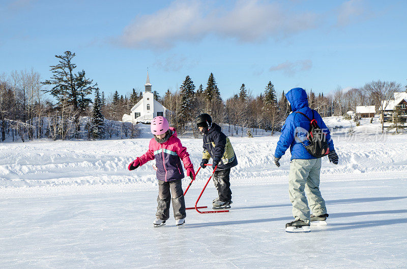冬天，母亲和孩子们在博波特湖镇的溜冰场上滑冰