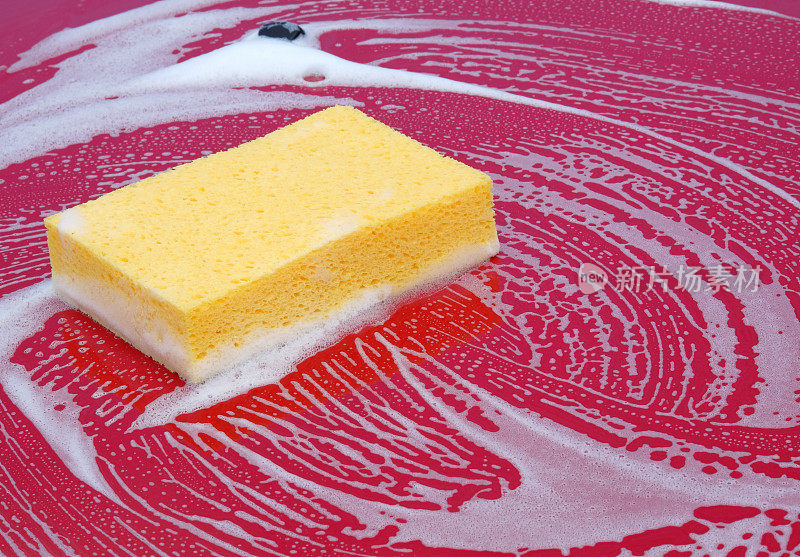 在洗车时，一块海绵在一辆红色汽车上的特写