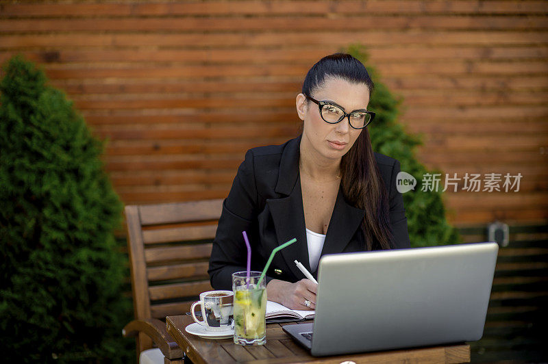 年轻的女商人在café用笔记本电脑工作