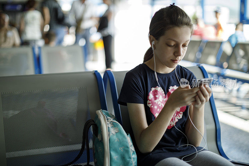 女性旅客在机场等候时使用手机