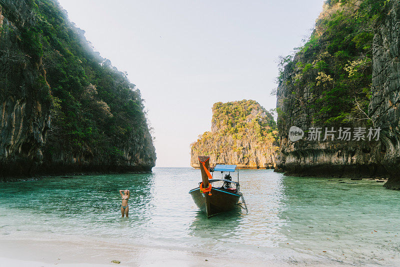 女人在大海附近的长尾船游泳