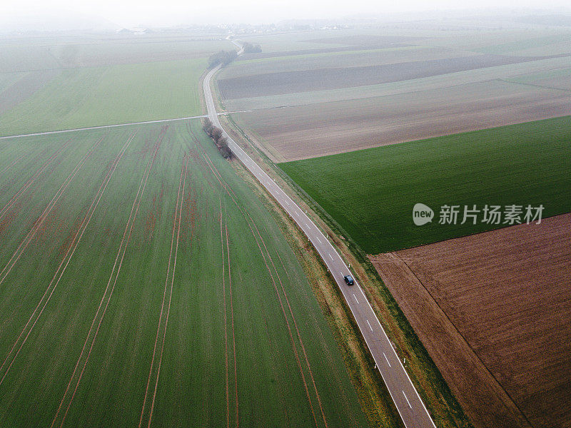 汽车鸟瞰图在雾蒙蒙的道路和丰富多彩的田野在德国