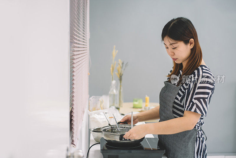 一位亚洲华人女性在加热水，准备她的工作室