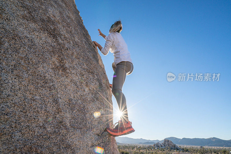 年轻女子攀登陡峭的巨石;人的户外活动概念