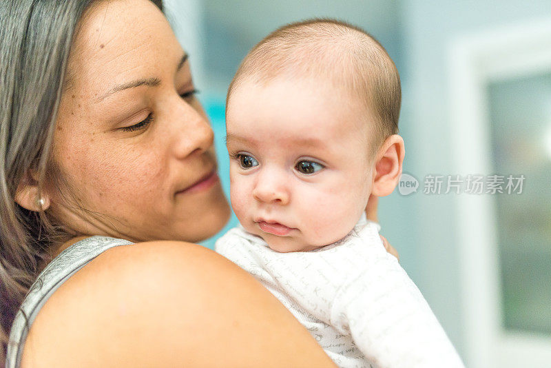 3个月大的可爱宝宝被妈妈抱在室内