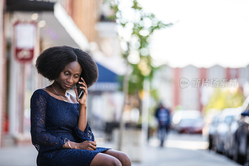 美丽的非洲裔美国妇女在一个小城市的街道上用手机说话