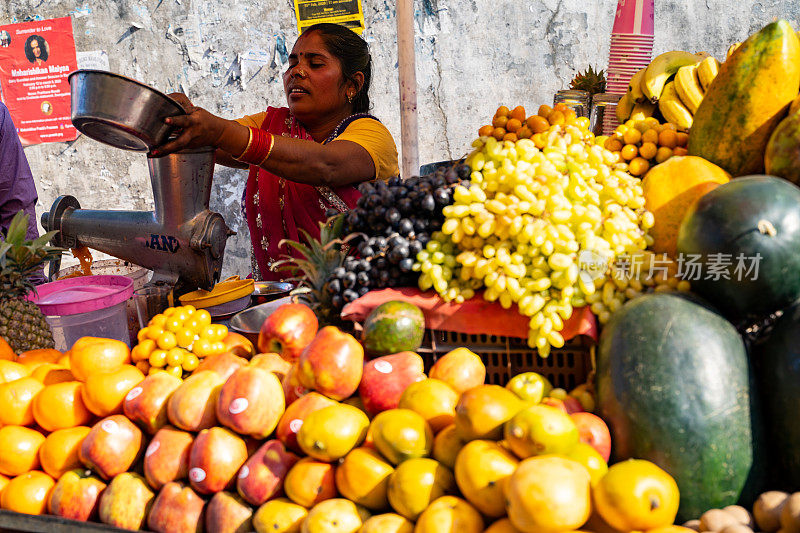 一名印度妇女在市场摊位上准备新鲜果汁卖给顾客