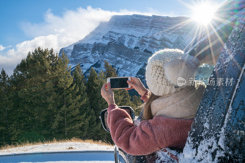 女人在车里冬天用手机，雪山