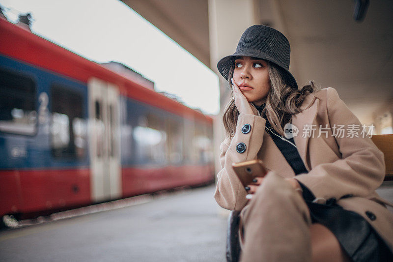 一个年轻的女人坐在火车站的长椅上