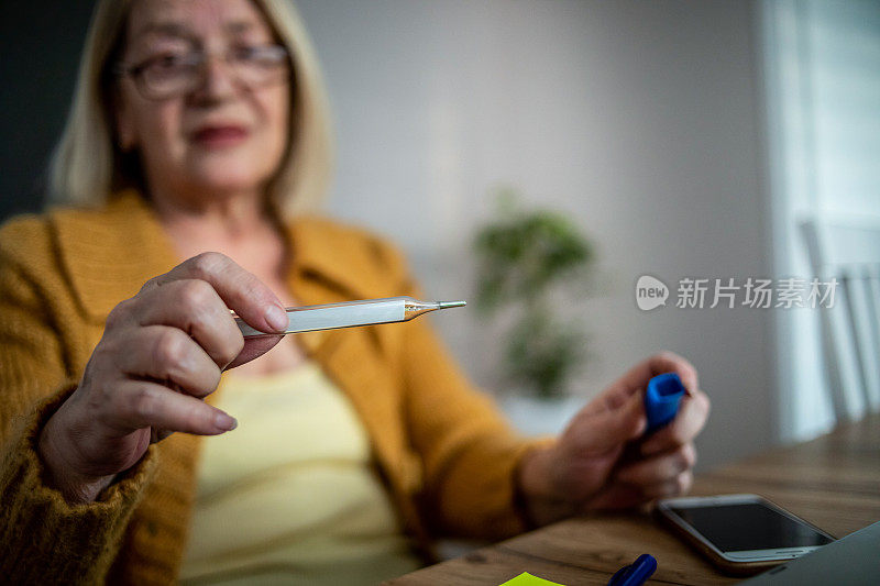 一位年长的妇女用体温计测体温
