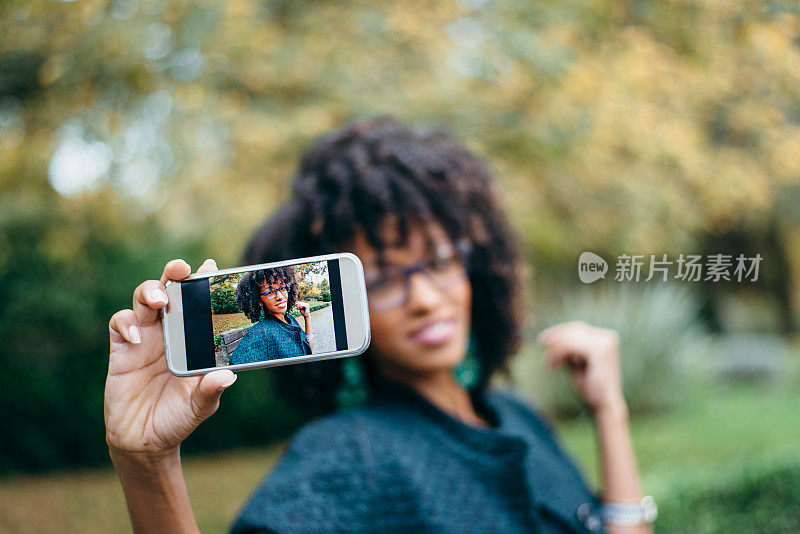 时尚黑人女性在秋天用智能手机自拍
