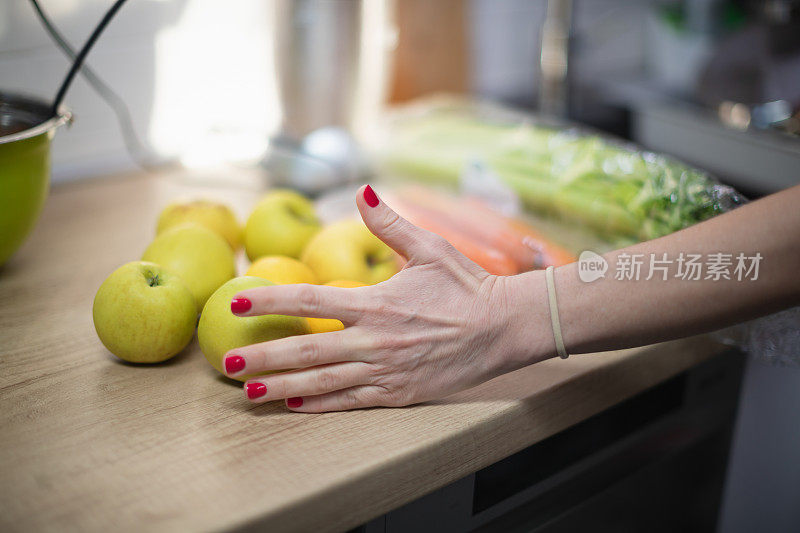 女人手拿着厨房柜台上的黄色苹果